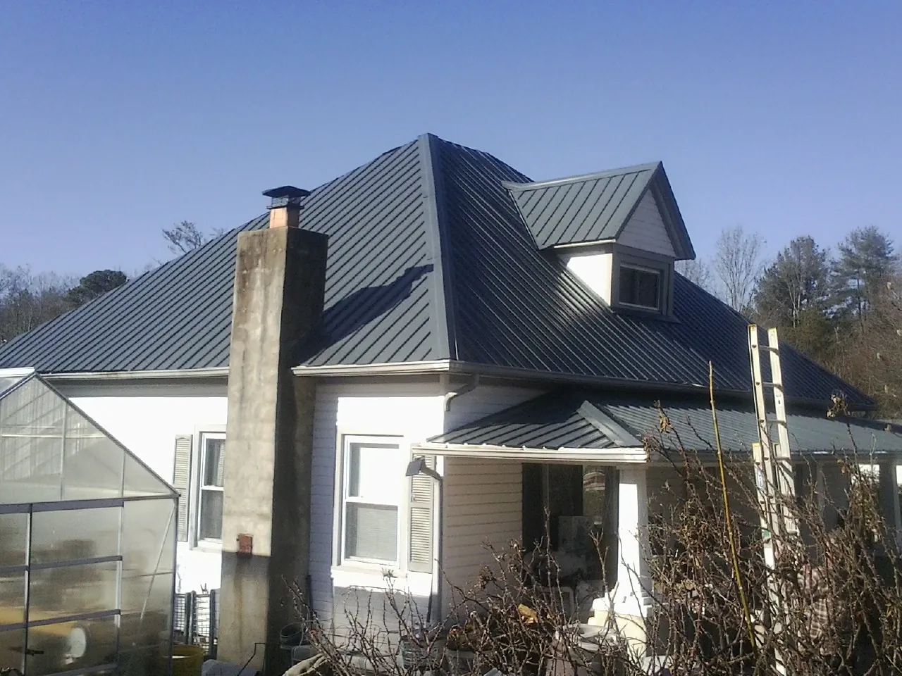 Dark blue standing seam metal roof on a white farmhouse with dormer — Slate & Tile Roof Repair by Roofing Brothers in East Hanover