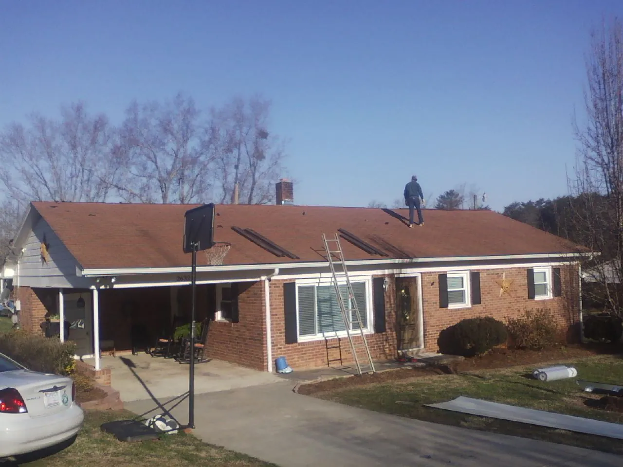 Roofer stripping a shingle roof on a brick ranch before metal panels in East Hanover