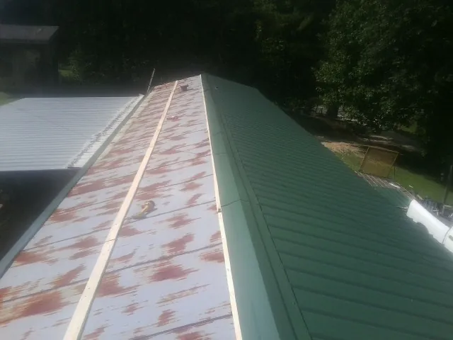 Old rusted panels beside newly installed green metal roofing — Wind Damage Roof Repair by Roofing Brothers in East Hanover