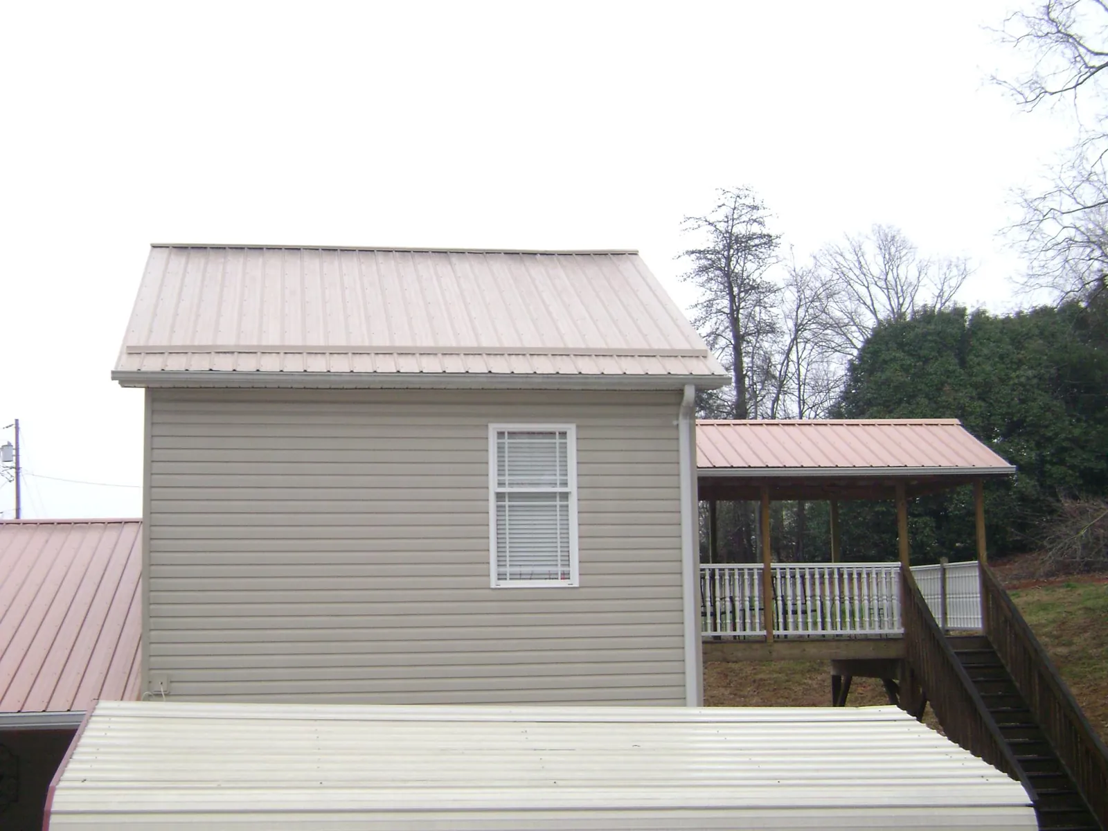 Tan metal roofs on a two story addition and attached porch, from a Roof Replacement job in East Hanover