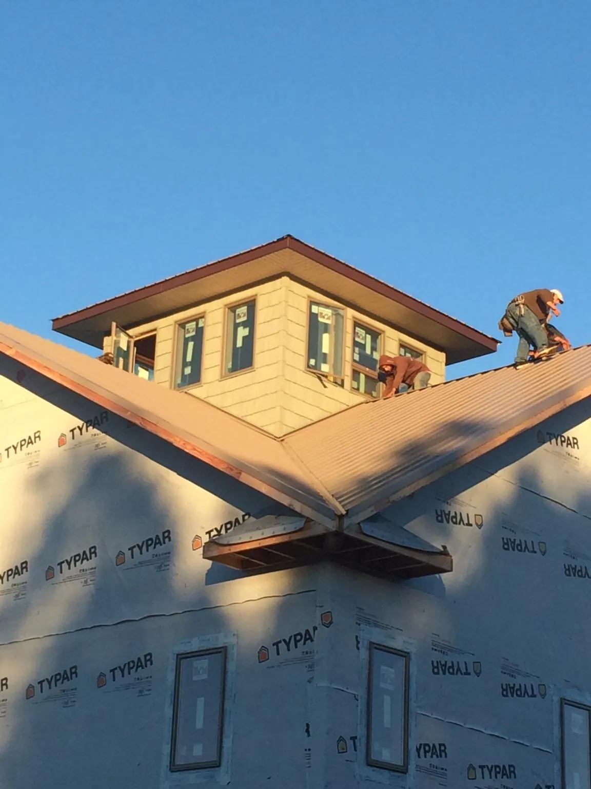 Roofers working around a rooftop cupola on a new metal roof at sunset — Roof Waterproofing in East Hanover by Roofing Brothers